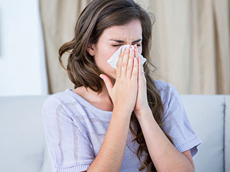 Female blowing nose and suffering from allergies