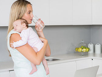 Female with a baby a glass of water in a kitchen