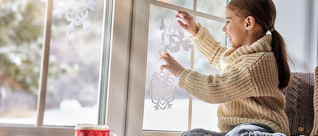 Child in a warm house playing with paper snowflakes